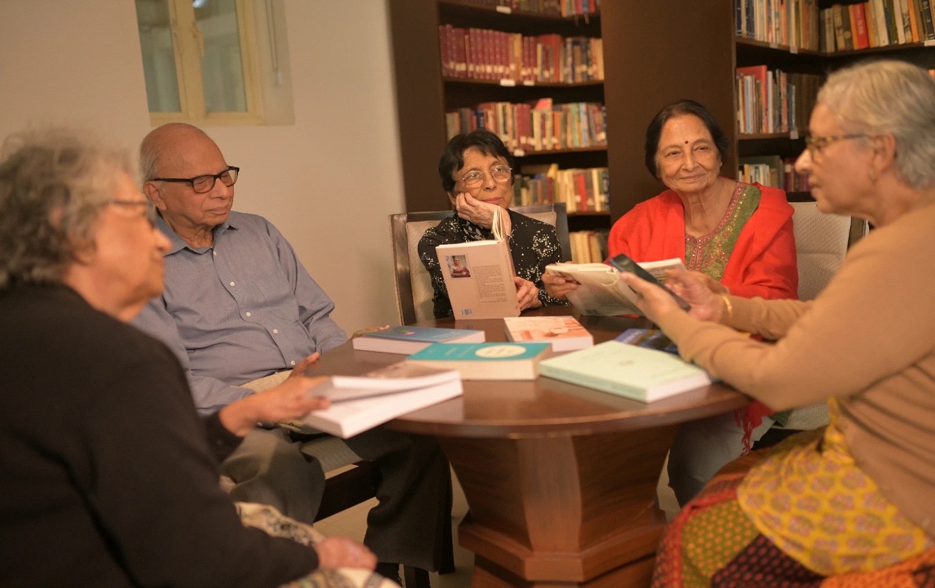 Seniors engaged in reading activities inside a cozy library at a retirement living community