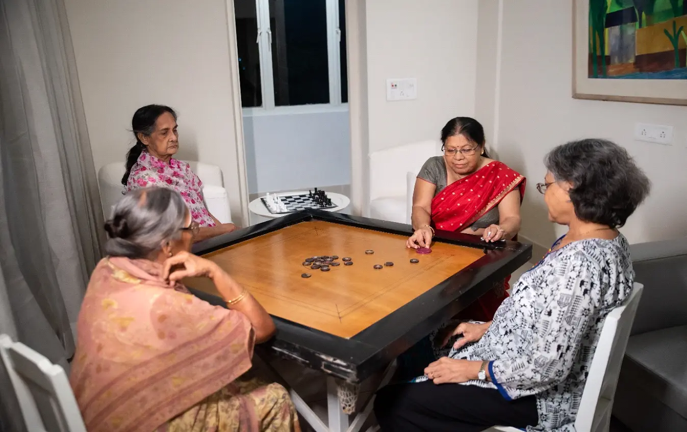 Future living senior citizen homes promoting social engagement with elderly women playing carrom.